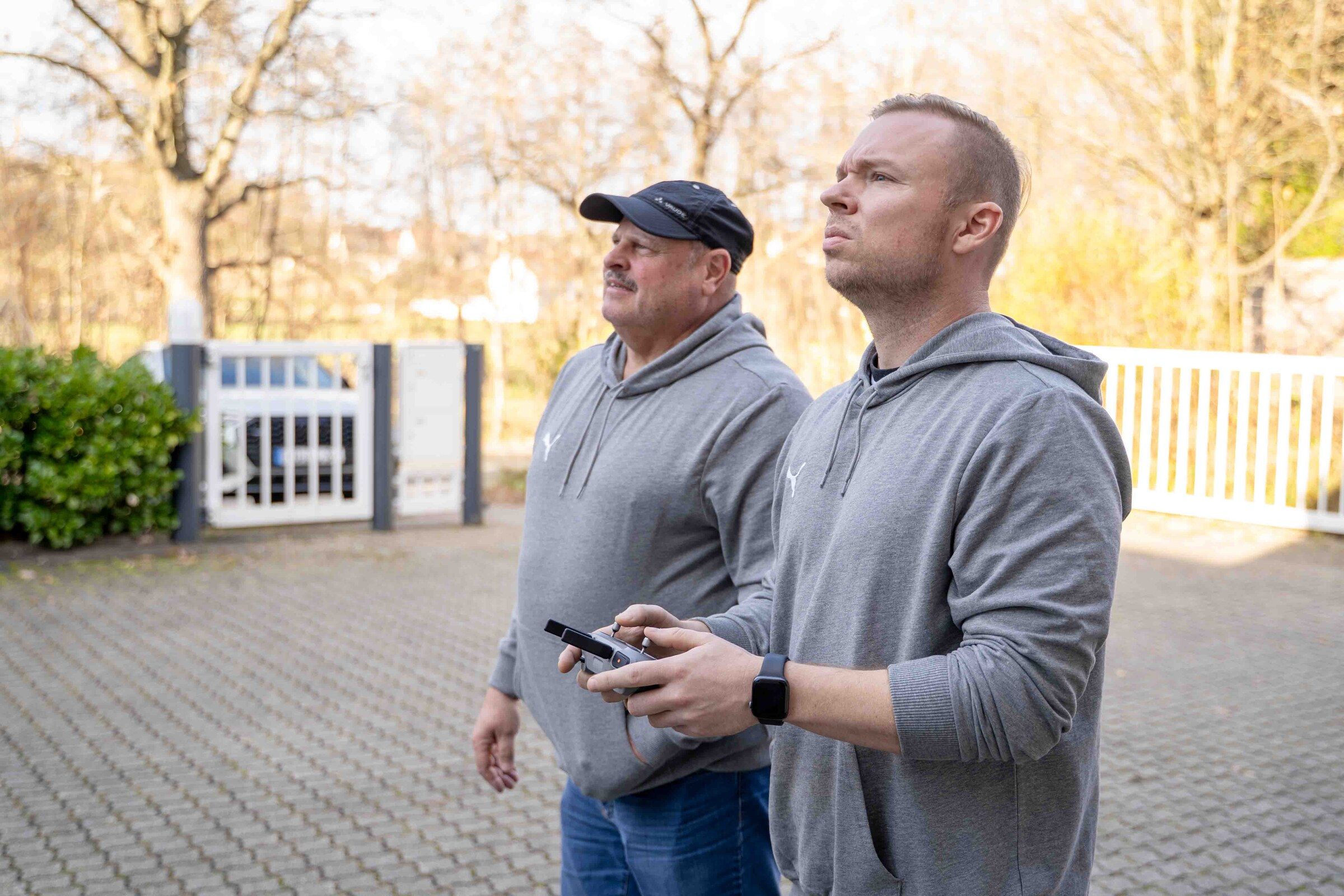 Zwei Mitarbeiter des Malerfachbetriebs Hertel steuern eine Drohne zur Fassadeninspektion